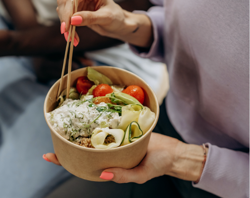 image of a bowl of food with a women eating it with chopsticks