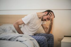 Man sitting on edge of bed, with stomach pain due to image of a someone pouring syrup over mint icecream in a bowel, this is used to demonstrate scenarios in the image of an emergency room to accompany the section where the person ends up in the emergency room due to food intolerance or food allergy problems